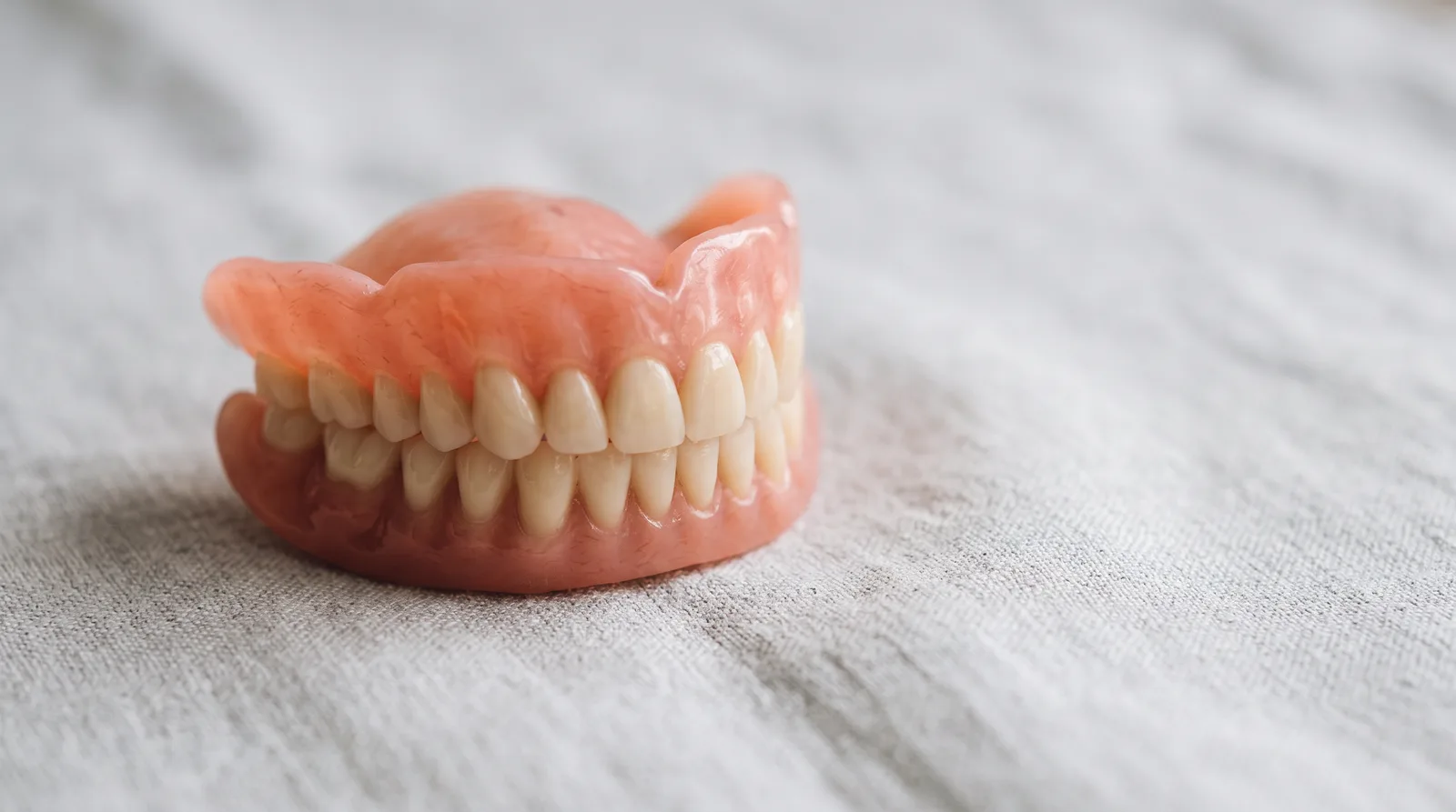 Modern full denture photographed on a soft grey surface