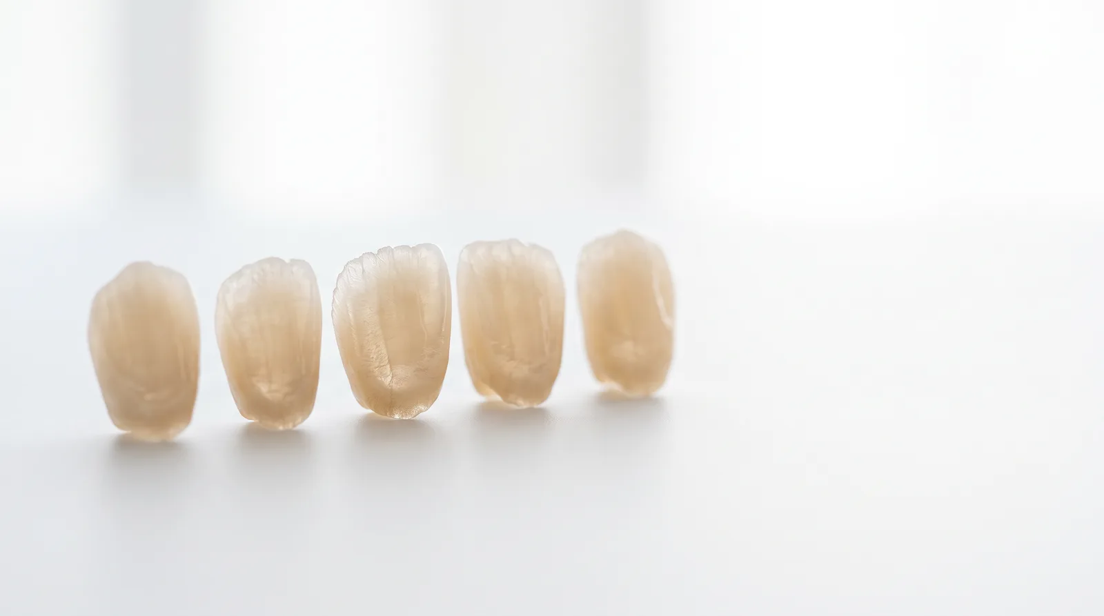 Thin porcelain veneer shells backlit to show their translucency