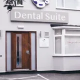 The front of TG's Dental Suite Ashby: the white building with the Tg's Dental Suite sign, wooden front door and bay window