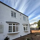 The white rendered TG's Dental Suite Earls Barton building, with the clinician name-board beside the bay window