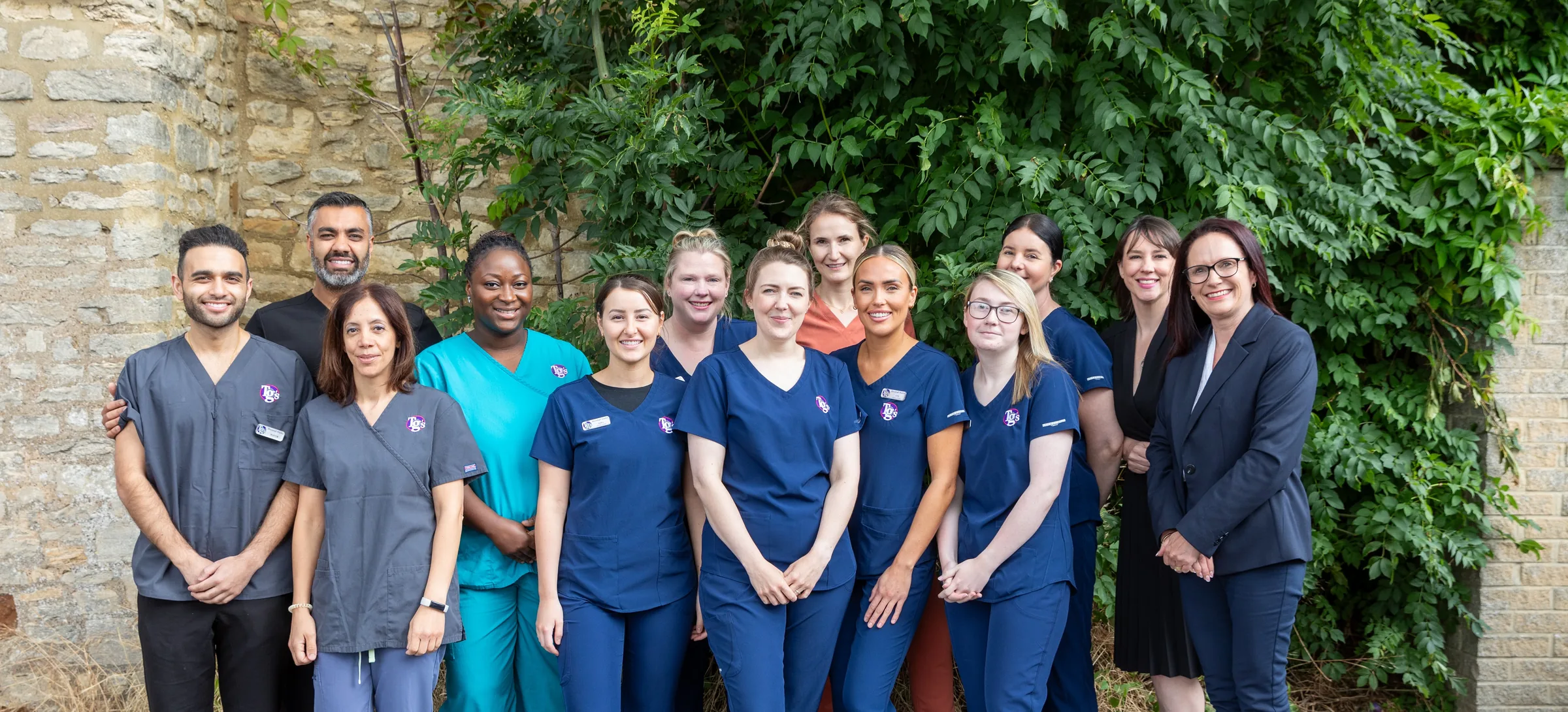 Twelve members of the TG's Dental Suite team outside the practice, in branded scrubs